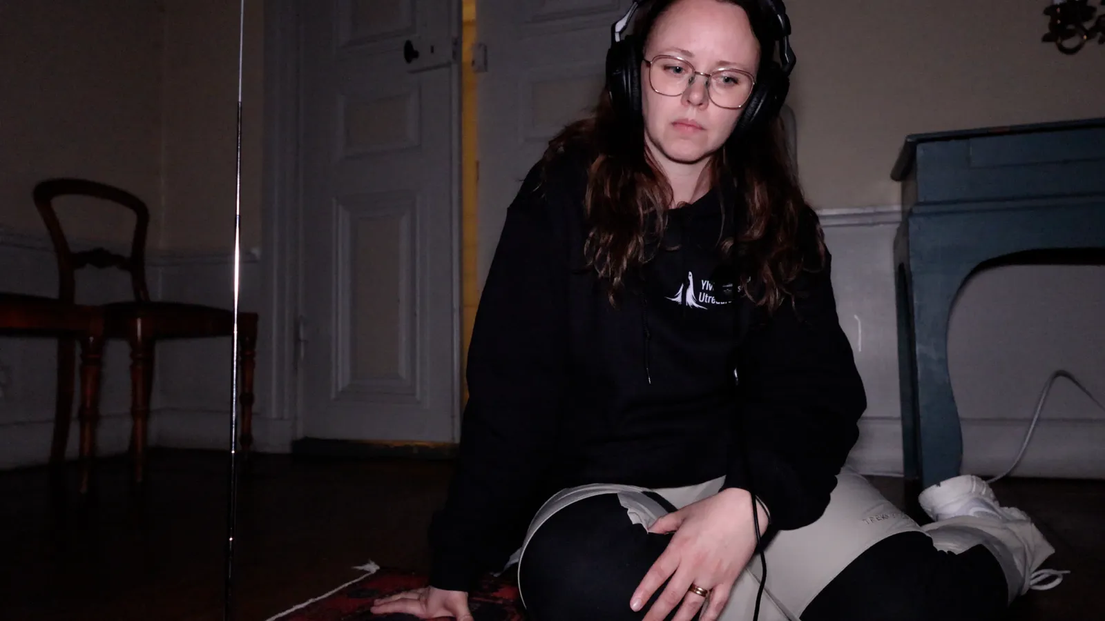 Ylva sitter på golvet med hörlurar och lyssnar av en inspelning under en utredning
