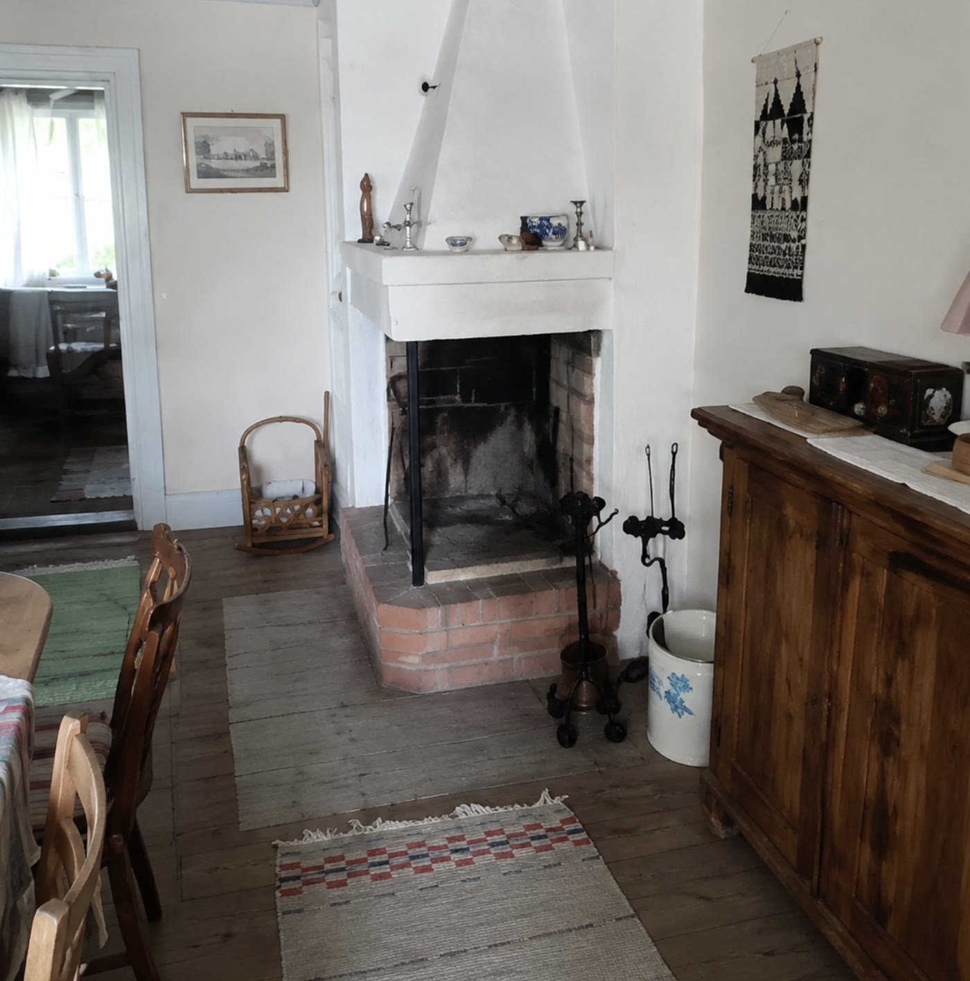 Den öppna spisen på Grums hembygdsgård med vitkalkad kåpa och trasmattor på golvet