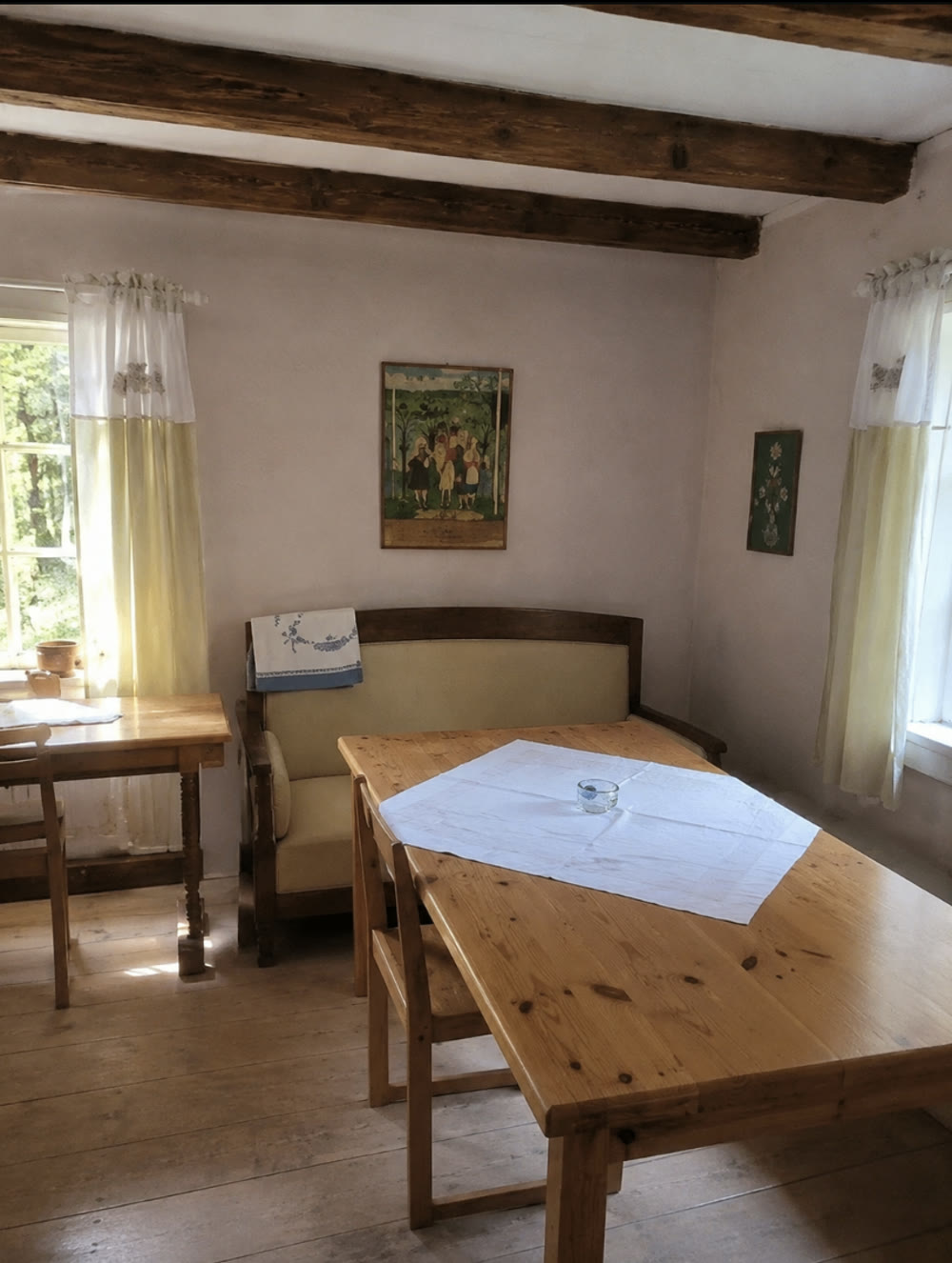 Rum på Grums hembygdsgård med synliga takbjälkar, gula gardiner och ett långbord
