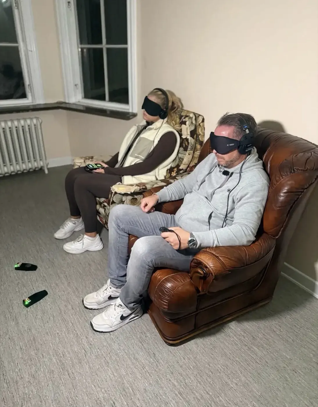 Två i teamet sitter med ögonbindel och hörlurar under en session, med mätare på golvet framför sig.