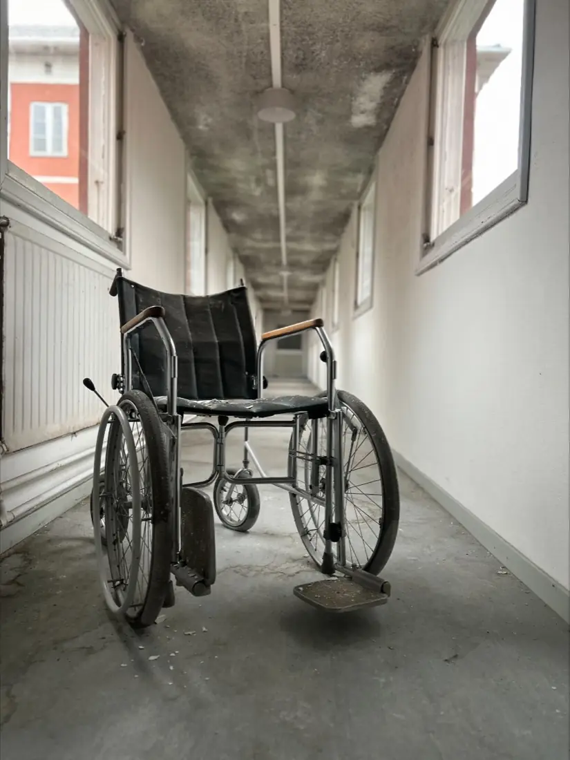 En kørestol står tilbage midt i en lys korridor på Sandträsk sanatorium