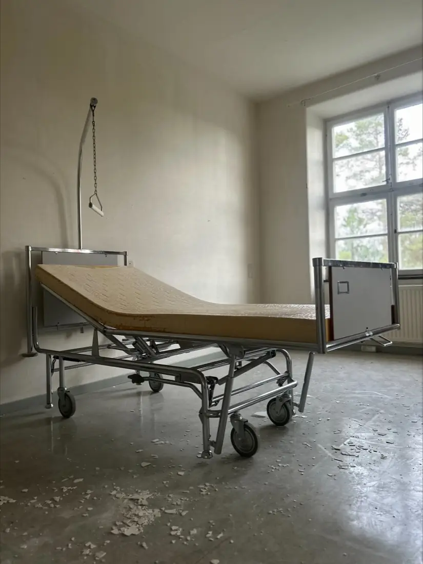 En hospitalsseng med efterladt madras i et tomt patientværelse